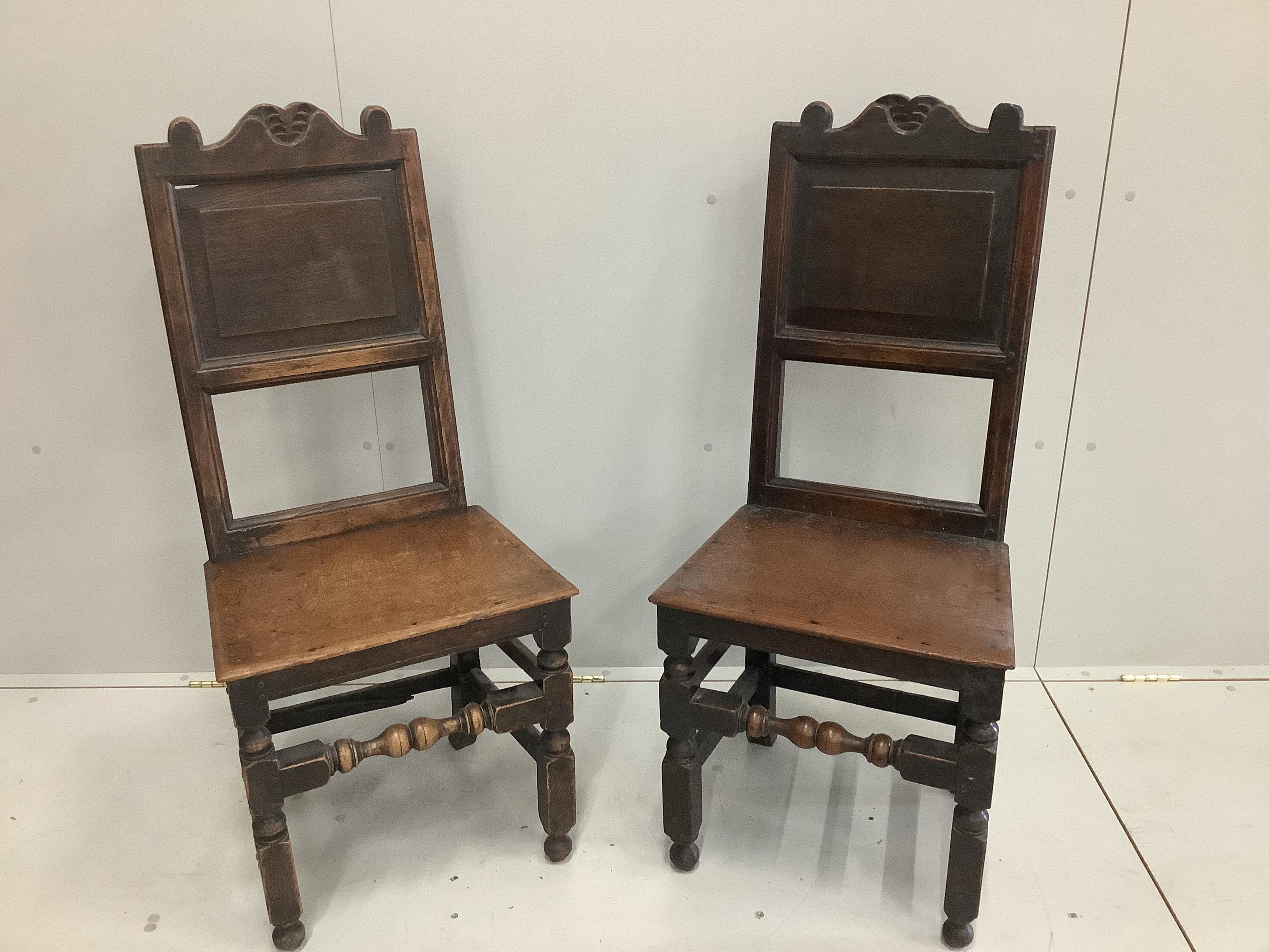 A pair of 17th century oak panel back chairs, width 47cm, height 108cm